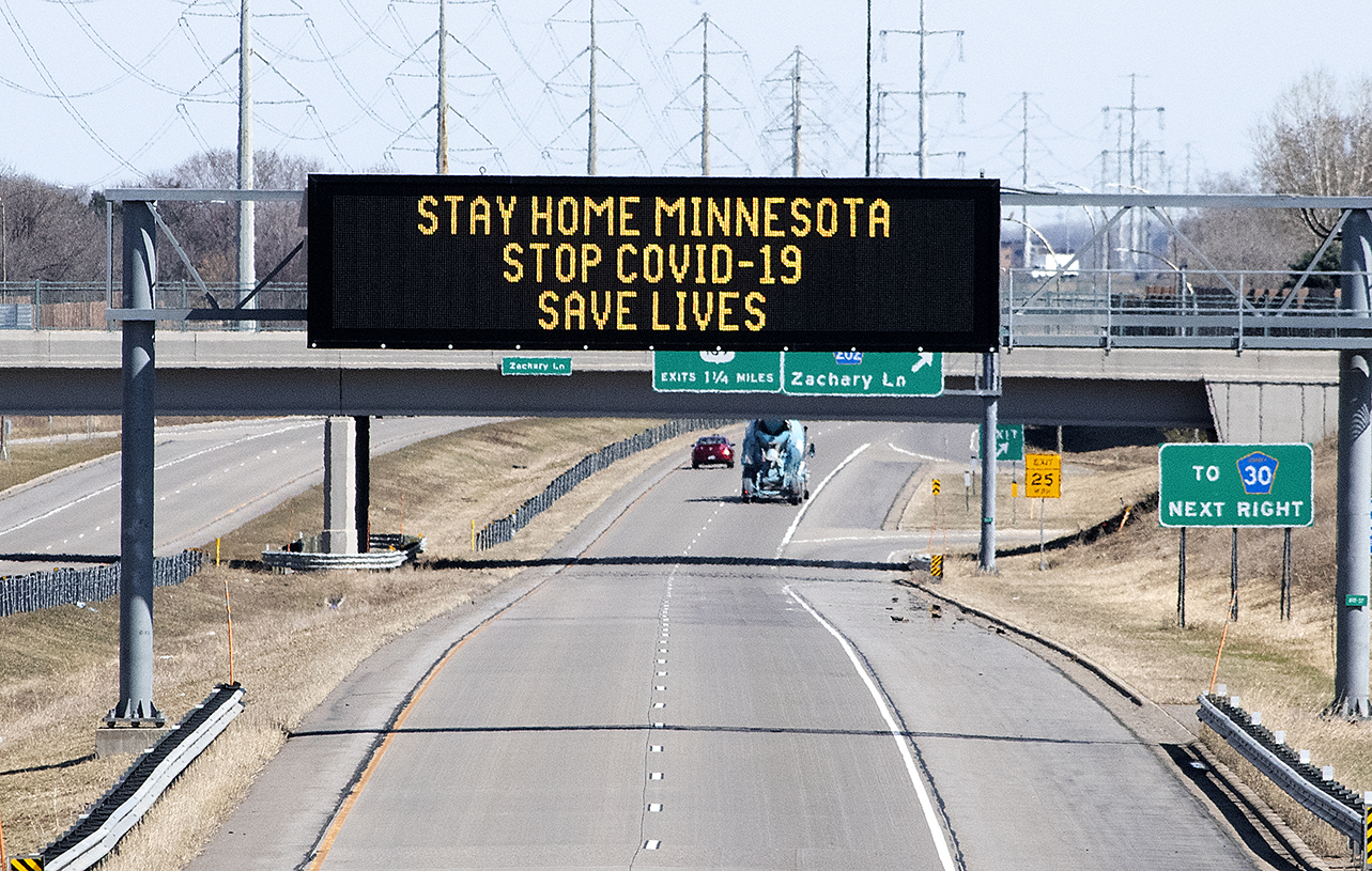 Photo: Electronic sign board displays the message stay home minnesota. Stop COVID 19. Save Lives